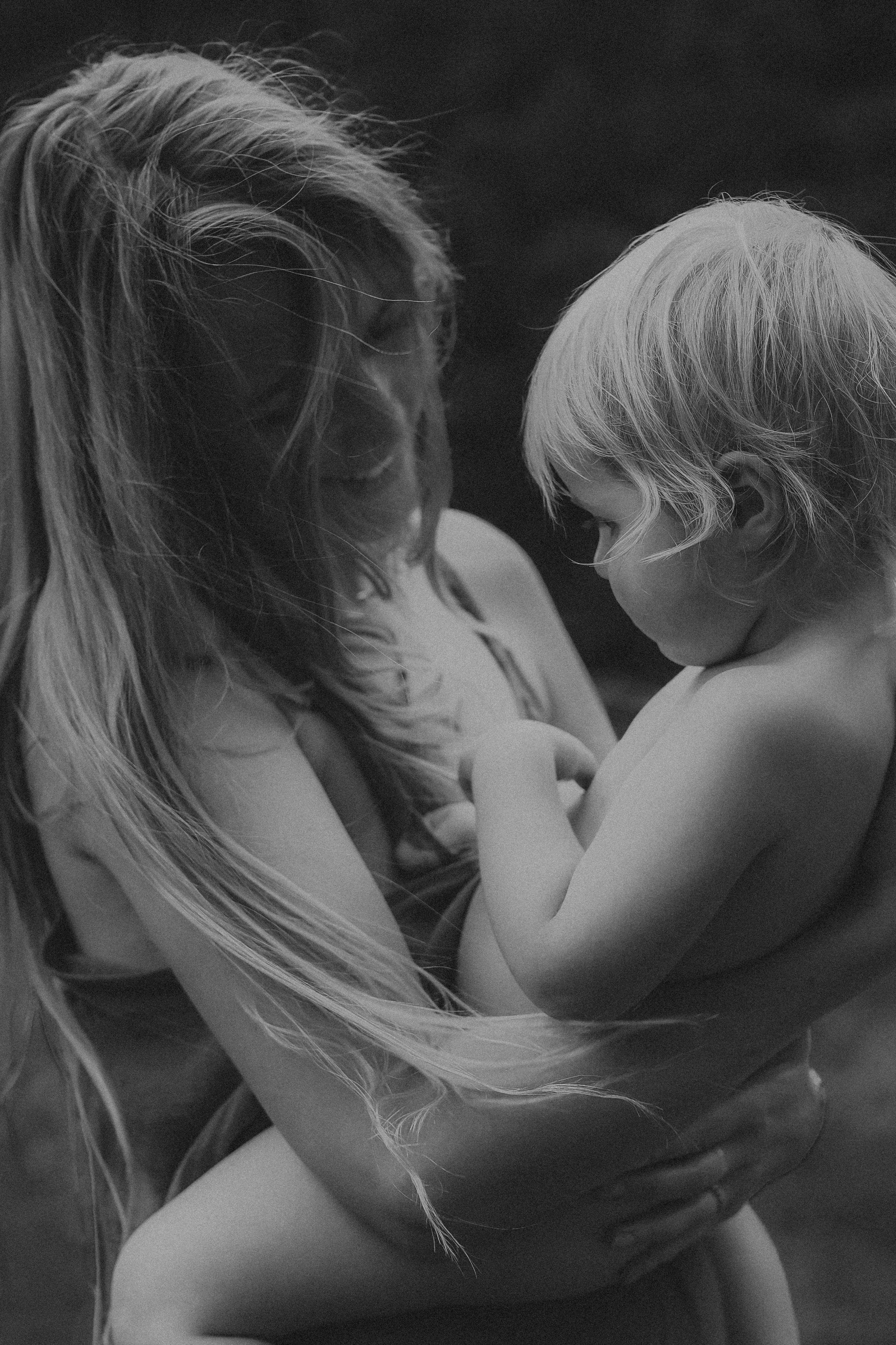 Black and white photo of mother tenderly holding young child outdoors.