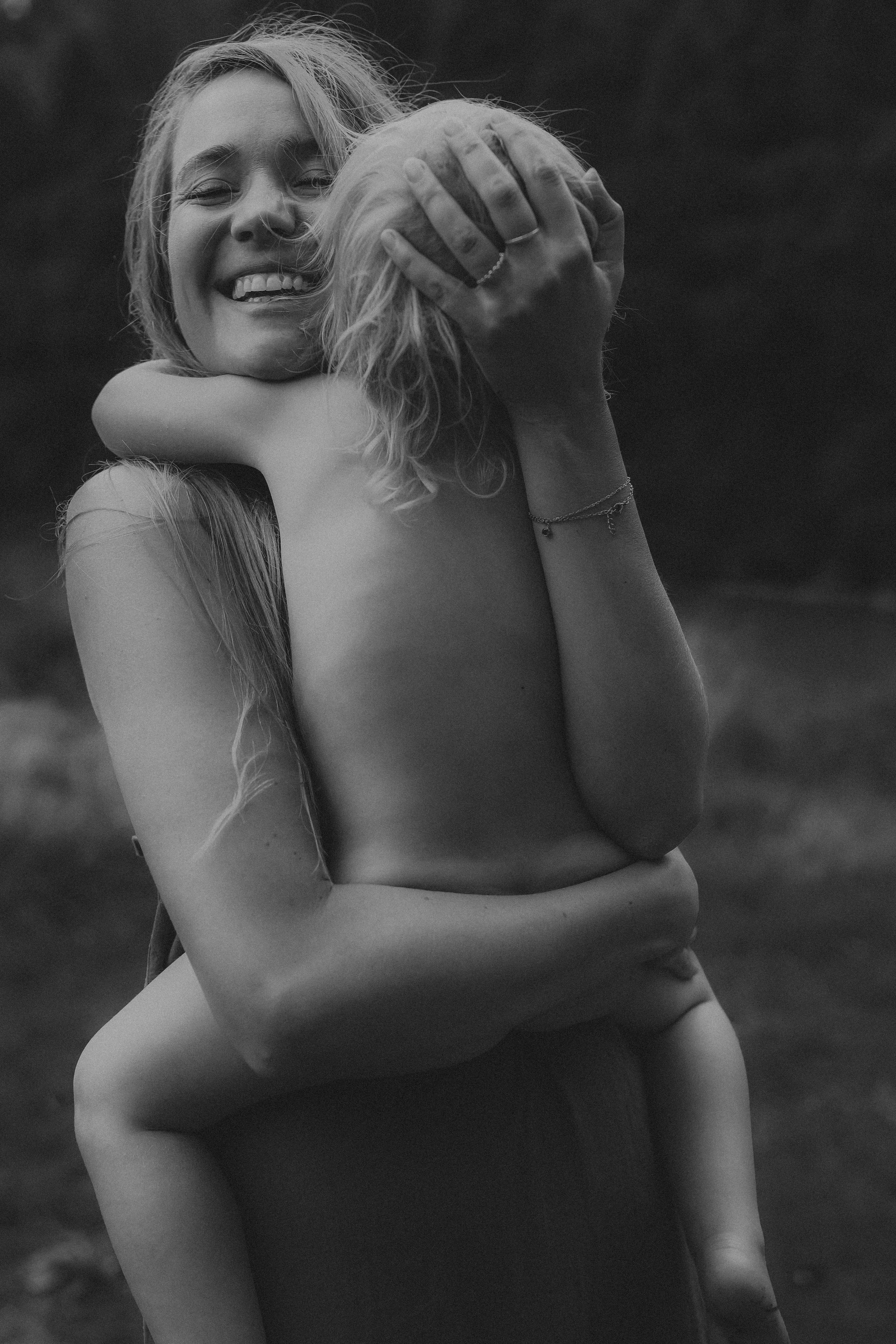 Smiling woman embracing a young child outdoors in black and white photo.