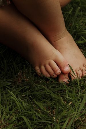 Close-up of a young child's bare feet sitting on green grass.
