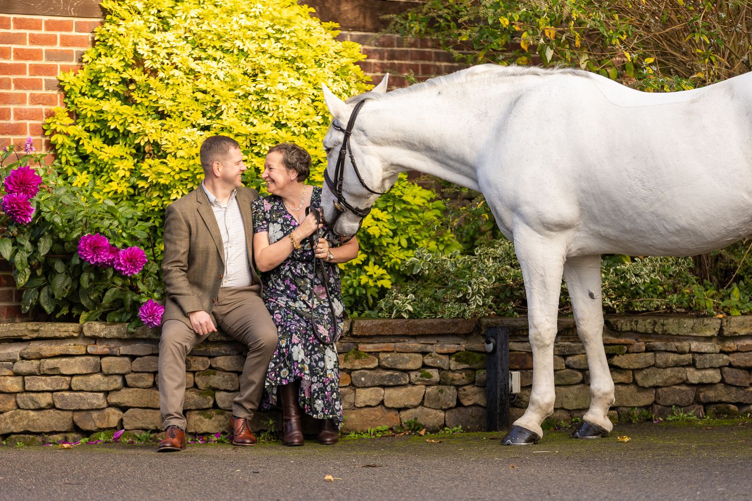 A black and white photograph shows a person sharing a tender moment with a dark horse in a stable.