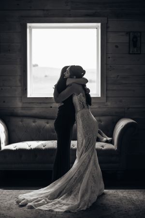 Artistic black and white photos of a bride in a lace gown posing near a window in a rustic wooden room.
