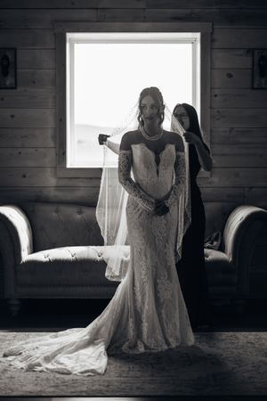 Black and white photos showcasing an elegant wedding dress with intricate lace details in a rustic wooden room.