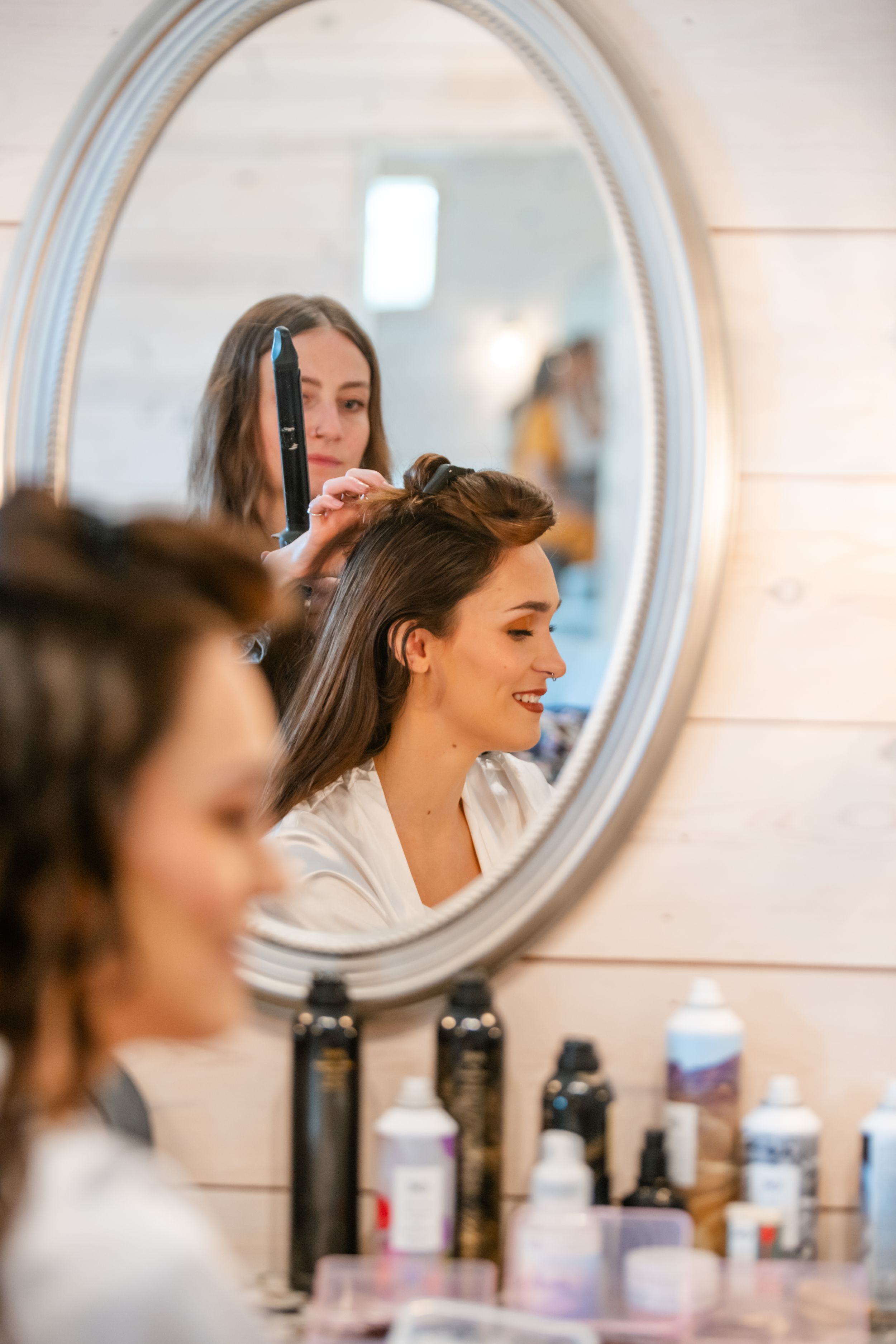 Getting ready in front of a round mirror with beauty products and hair styling tools.