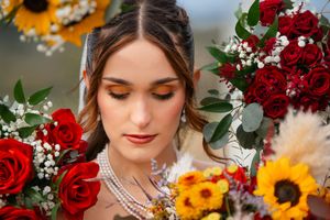 A bridal portrait with sunflowers and red roses in a romantic autumn wedding theme.