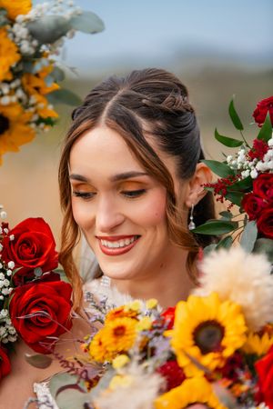 A bright bouquet of red roses and yellow sunflowers creates a vibrant wedding arrangement against a soft blurred background.