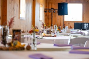 Rustic wooden barn reception setup with elegant table settings and natural lighting.