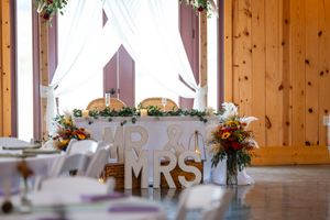 Wedding reception table with Mr & Mrs sign and floral arrangements in rustic wooden venue.