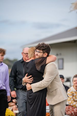 Emotional embrace between wedding guests during an outdoor ceremony.