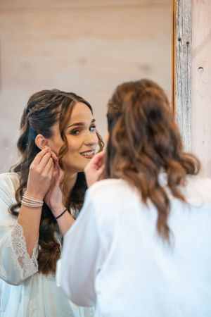 Two people share an intimate moment while getting ready, one wearing a white dress and the other in casual attire.
