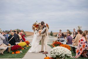 Outdoor wedding ceremony with fall decorations and white picket fence.
