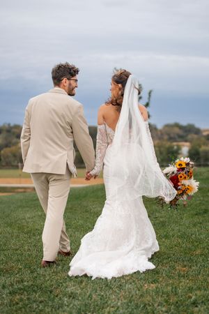 Couple walking together on grass field after their wedding ceremony in fall colors.
