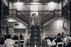 Black and white photo of wedding ceremony in grand venue with elegant staircase and columns.