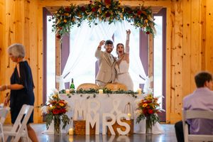 Wedding couple celebrates at reception under floral arch with Mr & Mrs sign.