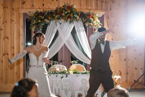 Indoor barn wedding reception with floral arch and string lights creating romantic ambiance.