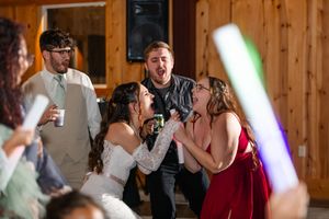 Wedding reception celebration in a rustic wooden barn venue with colorful lighting effects.