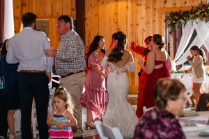 Wedding reception scene in a rustic wooden venue with warm lighting and guests mingling.