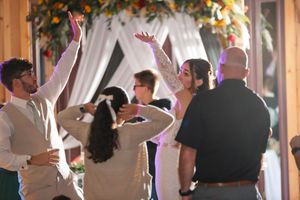 Wedding celebration in rustic barn venue with guests dancing under decorative lighting.