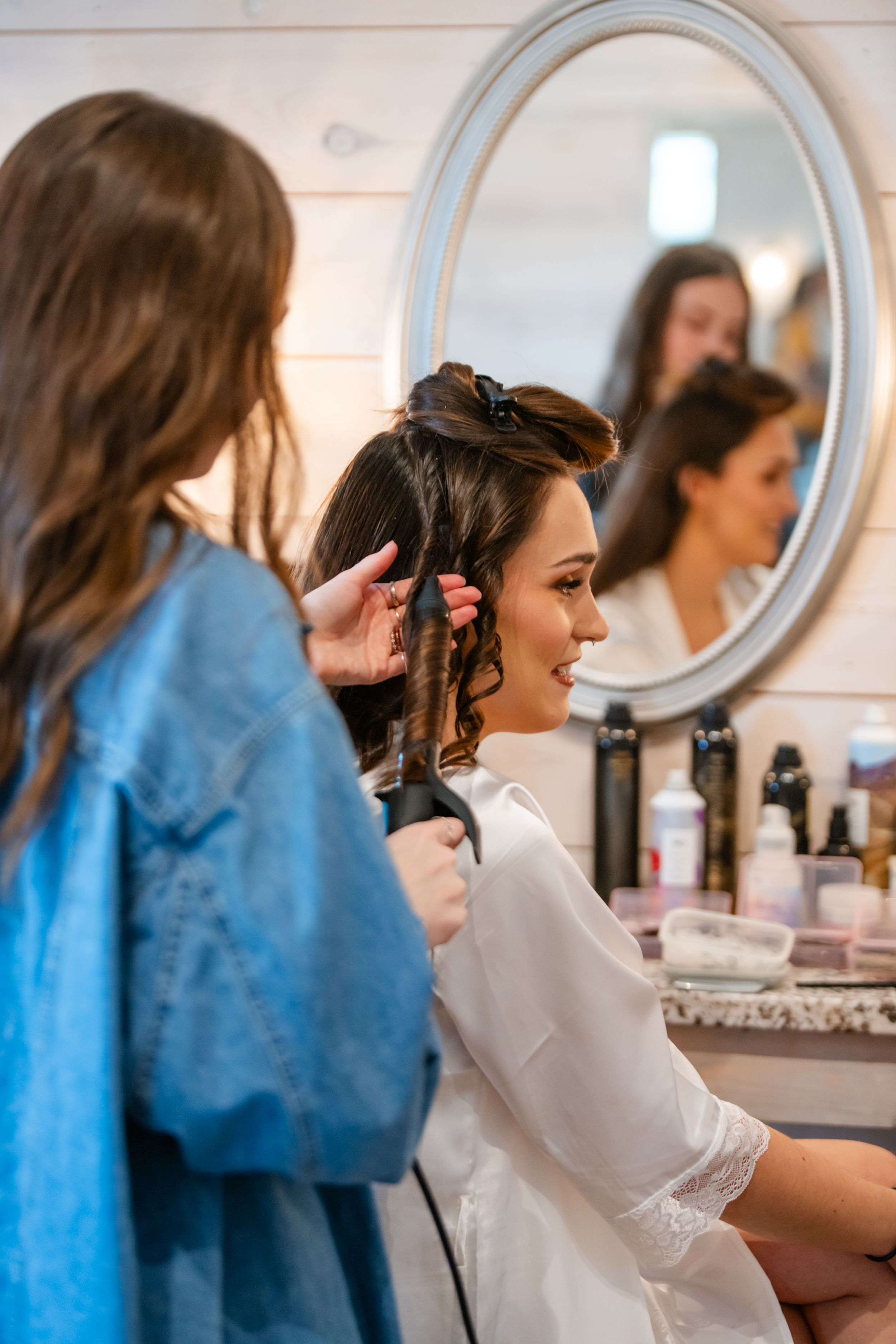 A sequence of images showing a person getting ready at a white vanity with round mirrors.