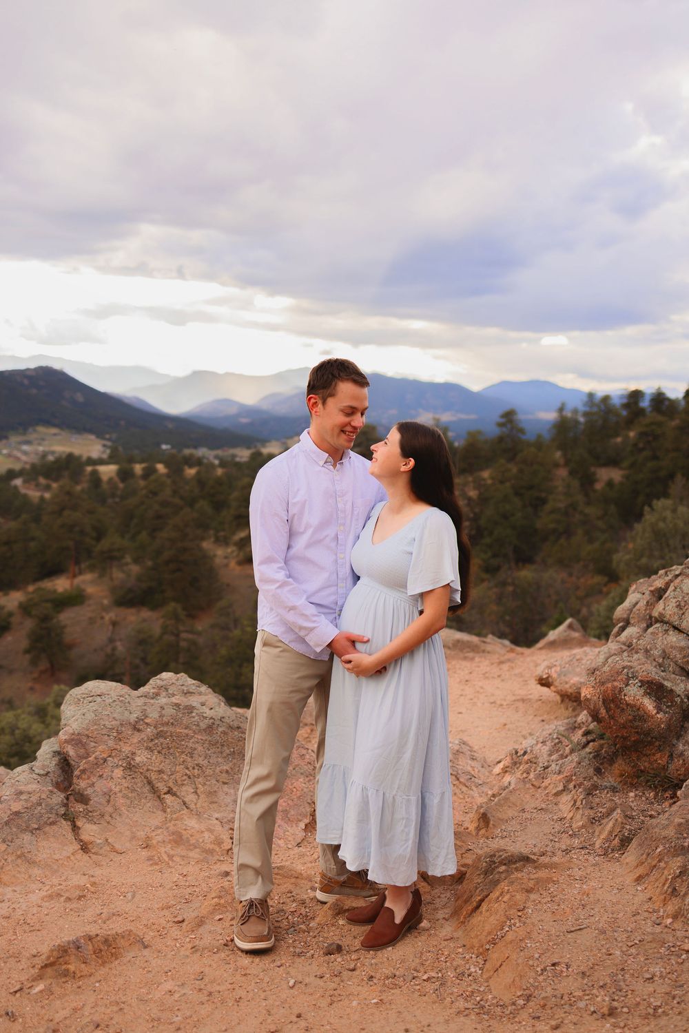 A couple shares a romantic moment against a scenic mountain backdrop in Colorado's Mt Falcon