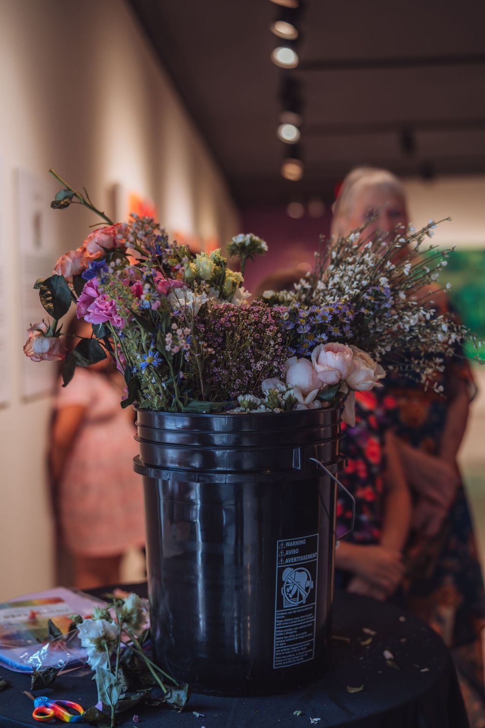 Black plastic buckets filled with dried flowers sit in a row on display.