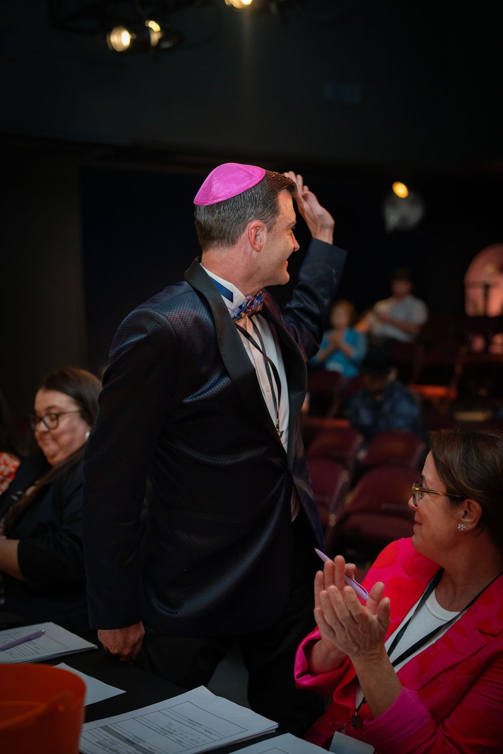 Judges in formal attire evaluate performances from theater seats.
