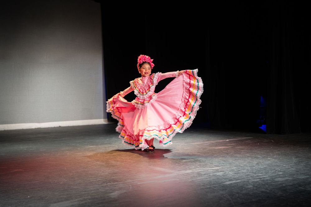 Dancer in pink dress performing expressive floor movements on stage.