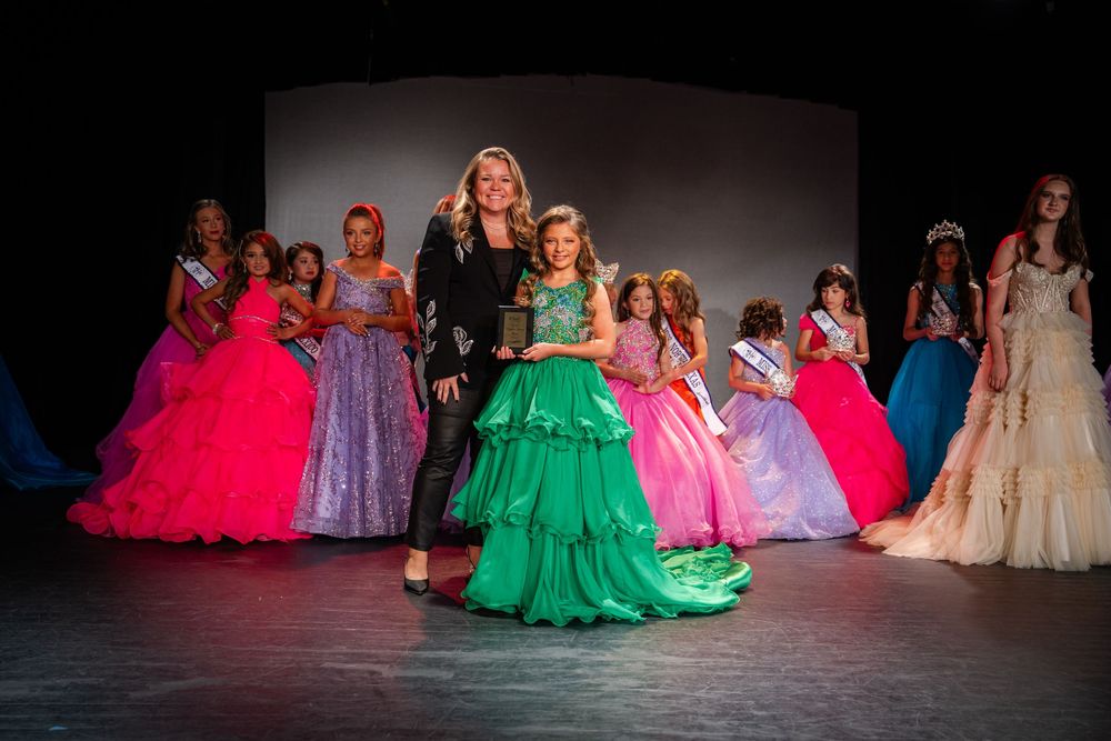 Contestants in vibrant ball gowns perform on stage during a pageant show.
