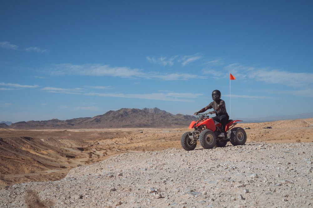 Desert landscape with mountains and off-road vehicle tracks in the dry terrain.