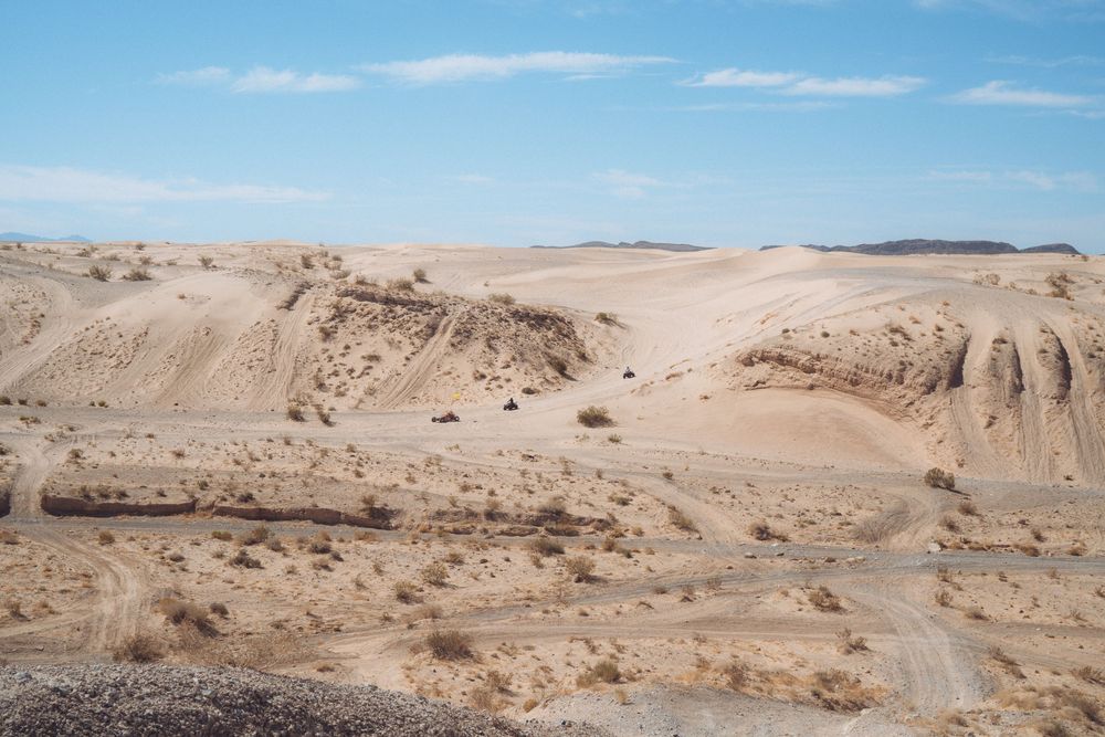 Sandy desert landscape with rolling hills and clear blue skies stretching to the horizon.