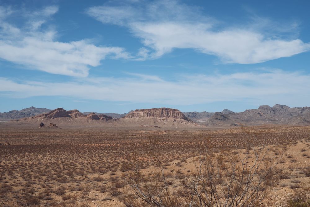 Vast desert panorama showing mountains and sparse vegetation under bright blue skies.