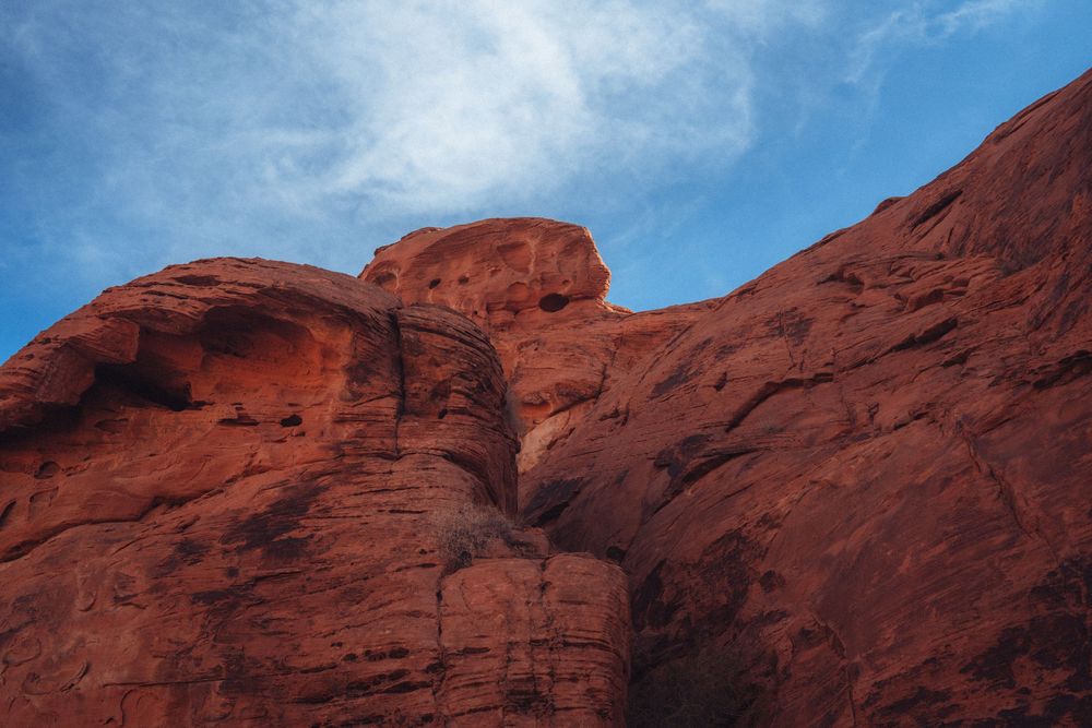 Dramatic red sandstone cliffs and rock formations against a bright blue desert sky.
