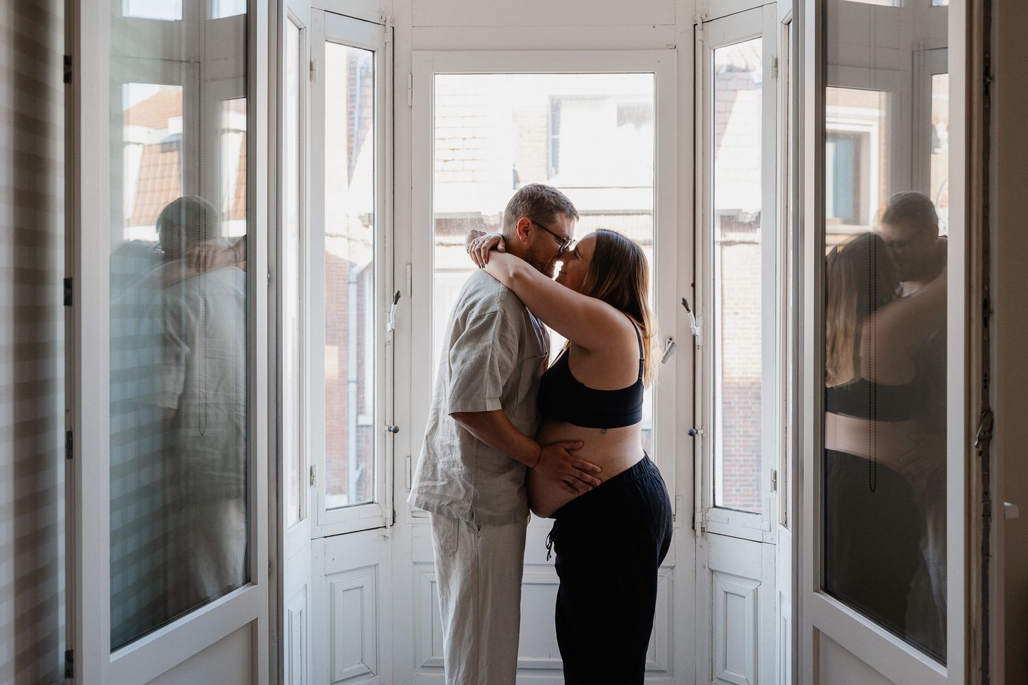 Shooting grossesse Lille, photo d'un couple attendant son premier bebe avec des reflets dans les fenetres