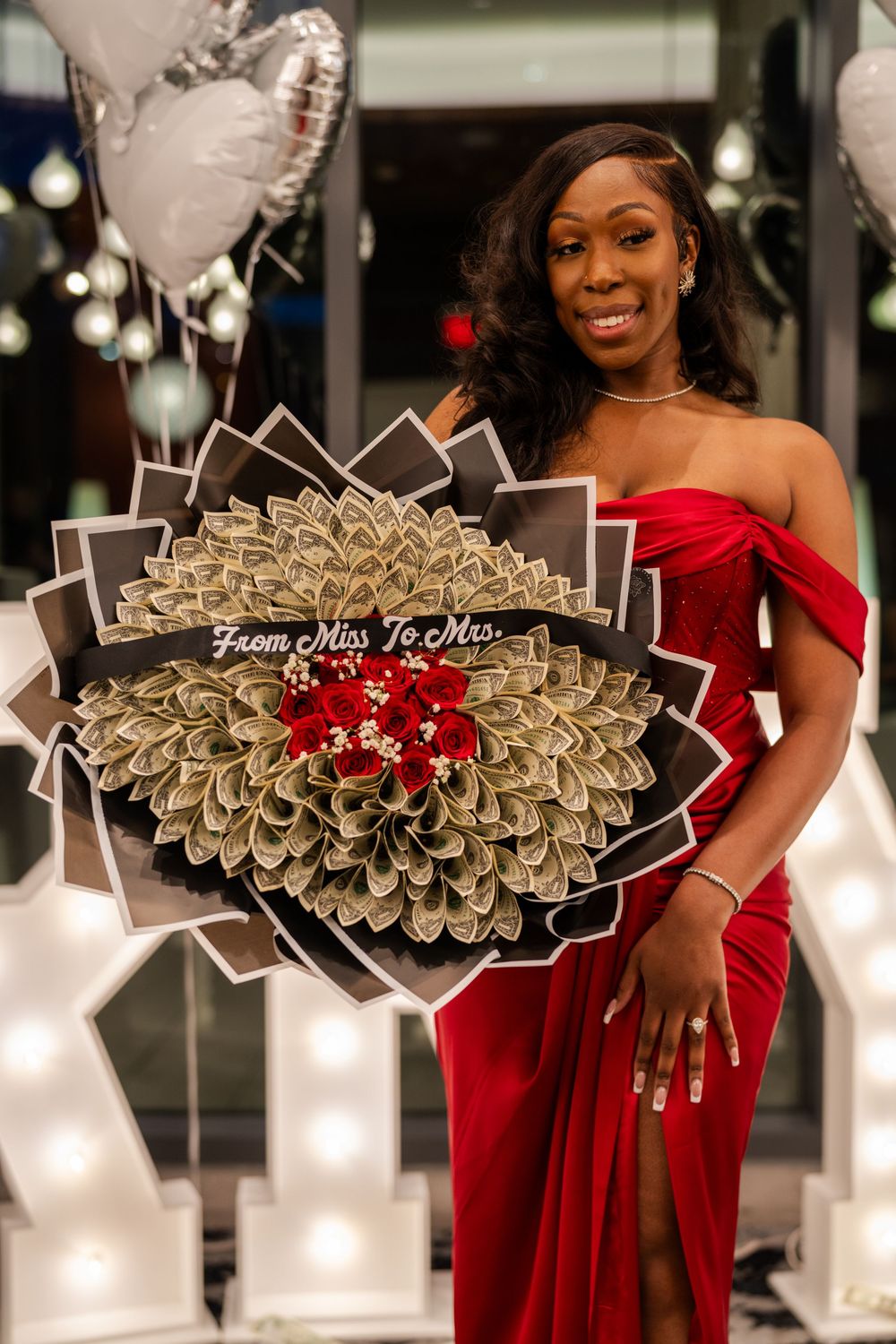 Decorative money bouquets with red roses and 'From Miss To Mrs' text displayed at an elegant event.