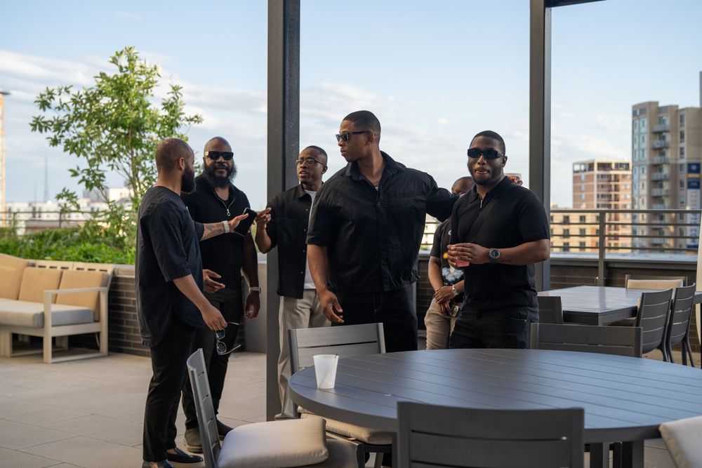 People socializing on a modern rooftop terrace with city views.