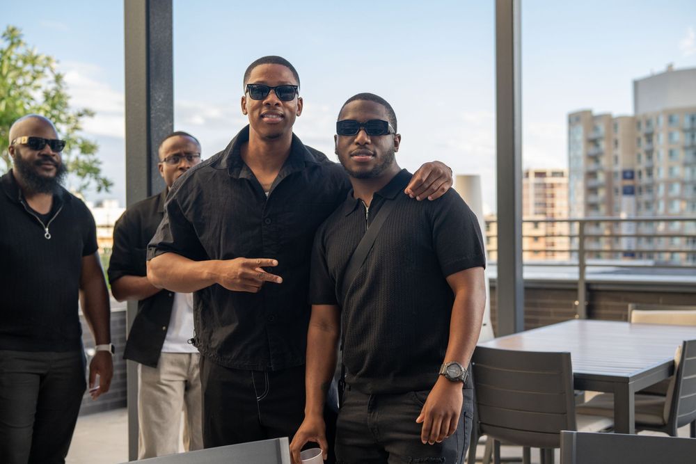 Group of guests in black attire enjoying a rooftop gathering.