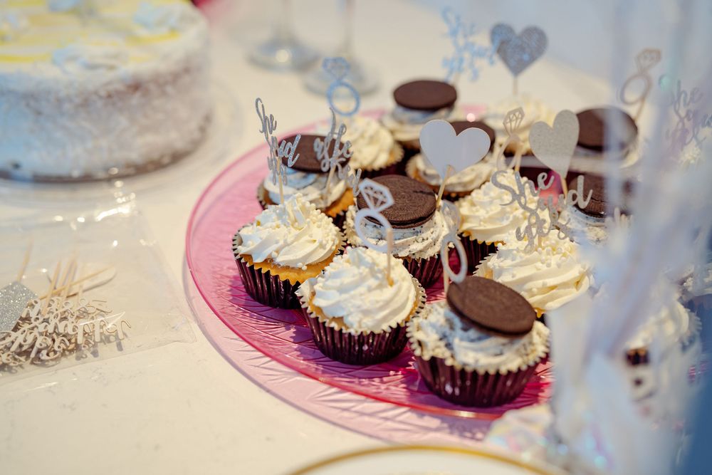 Elegant cupcakes with white frosting and chocolate decorations on pink plates.