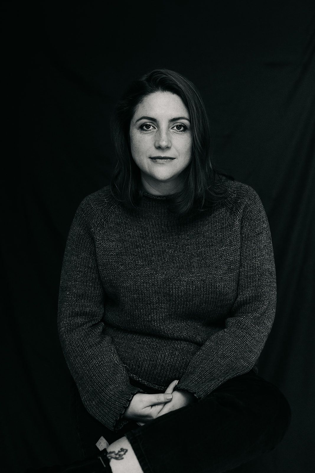 Artistic black and white portrait series showing a person in dark sweater against black background . Author headshots Hampshire