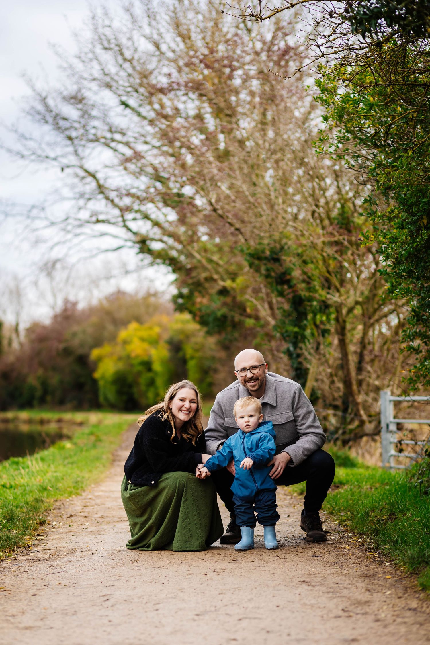 A family sits together on a dirt path at Parbold Canal surrounded by trees in a natural outdoor setting captured by Lancashire Photographer