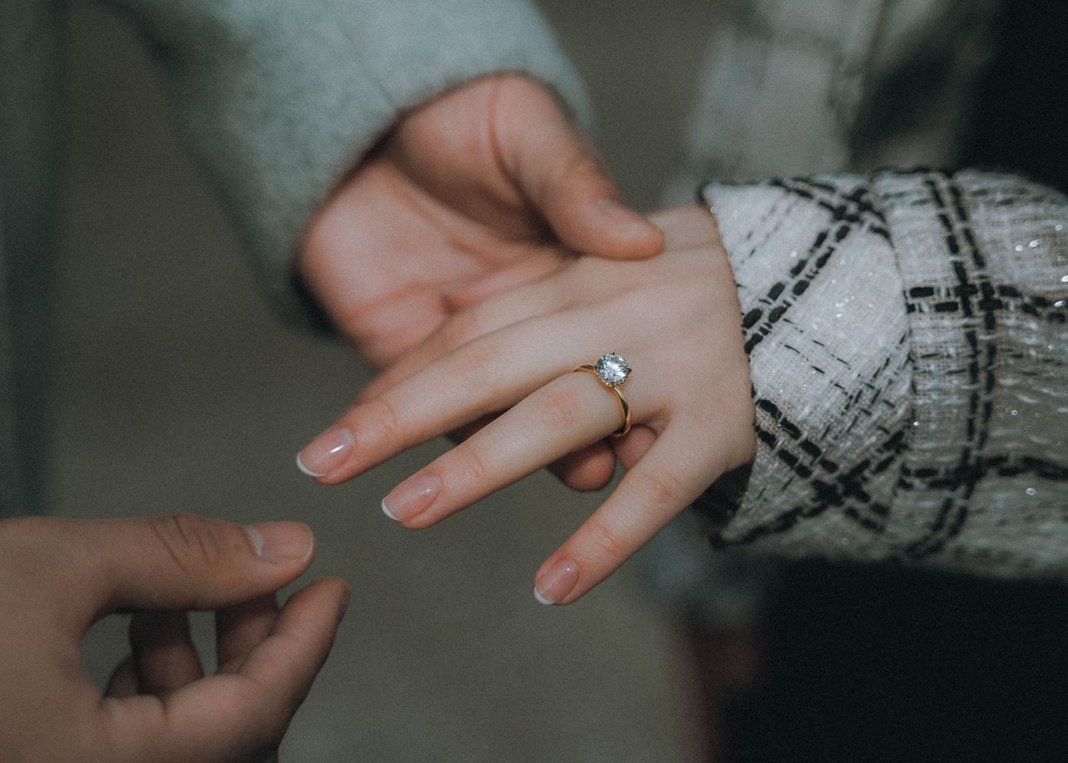 An open book held by hands with sparkly nail polish against a dark background with Christmas lights.