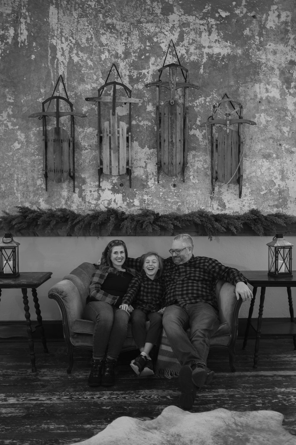 Black and white indoor portrait with decorative metal wall art of gothic arches hanging above a couch in a rustic setting.