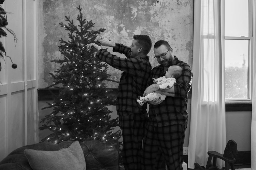 Black and white photo collage showing holiday scenes with Christmas trees and people decorating inside a cozy home.