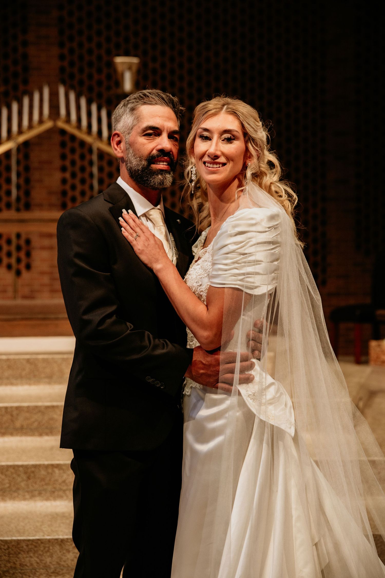 A formal wedding portrait in an elegant church setting with ornate architectural details.
