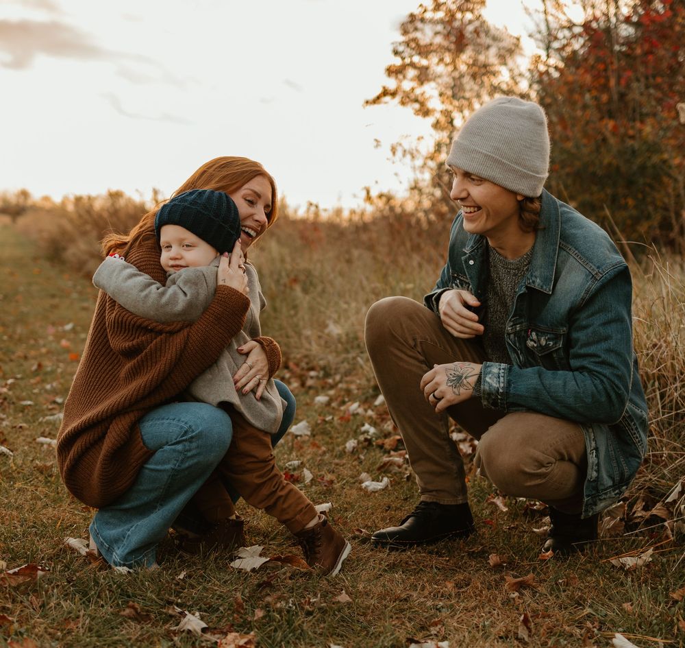 Family playing together in autumn field during golden hour.