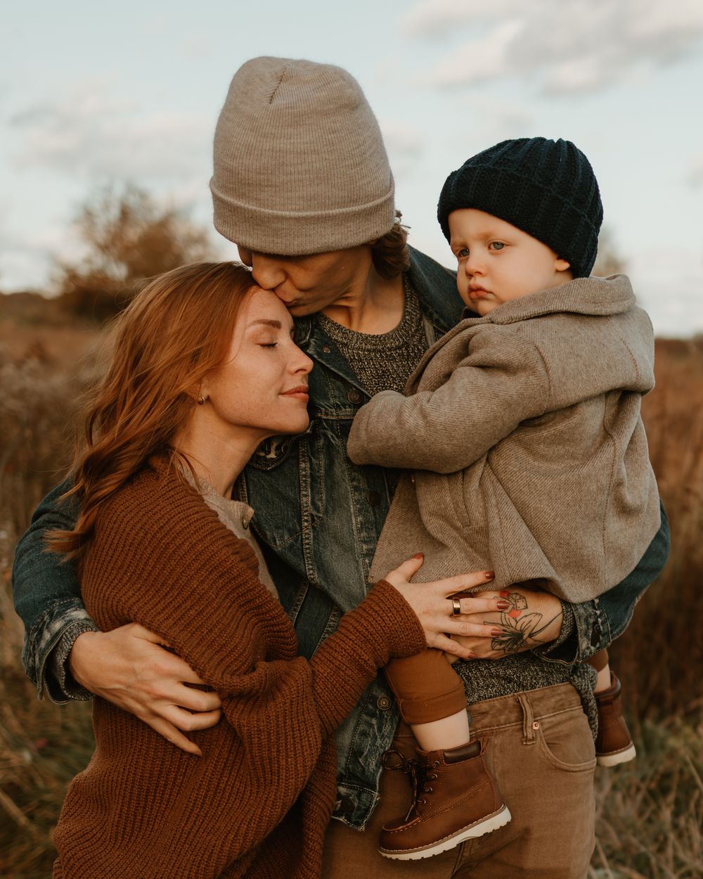 Warm family embrace outdoors during fall season wearing cozy sweaters.