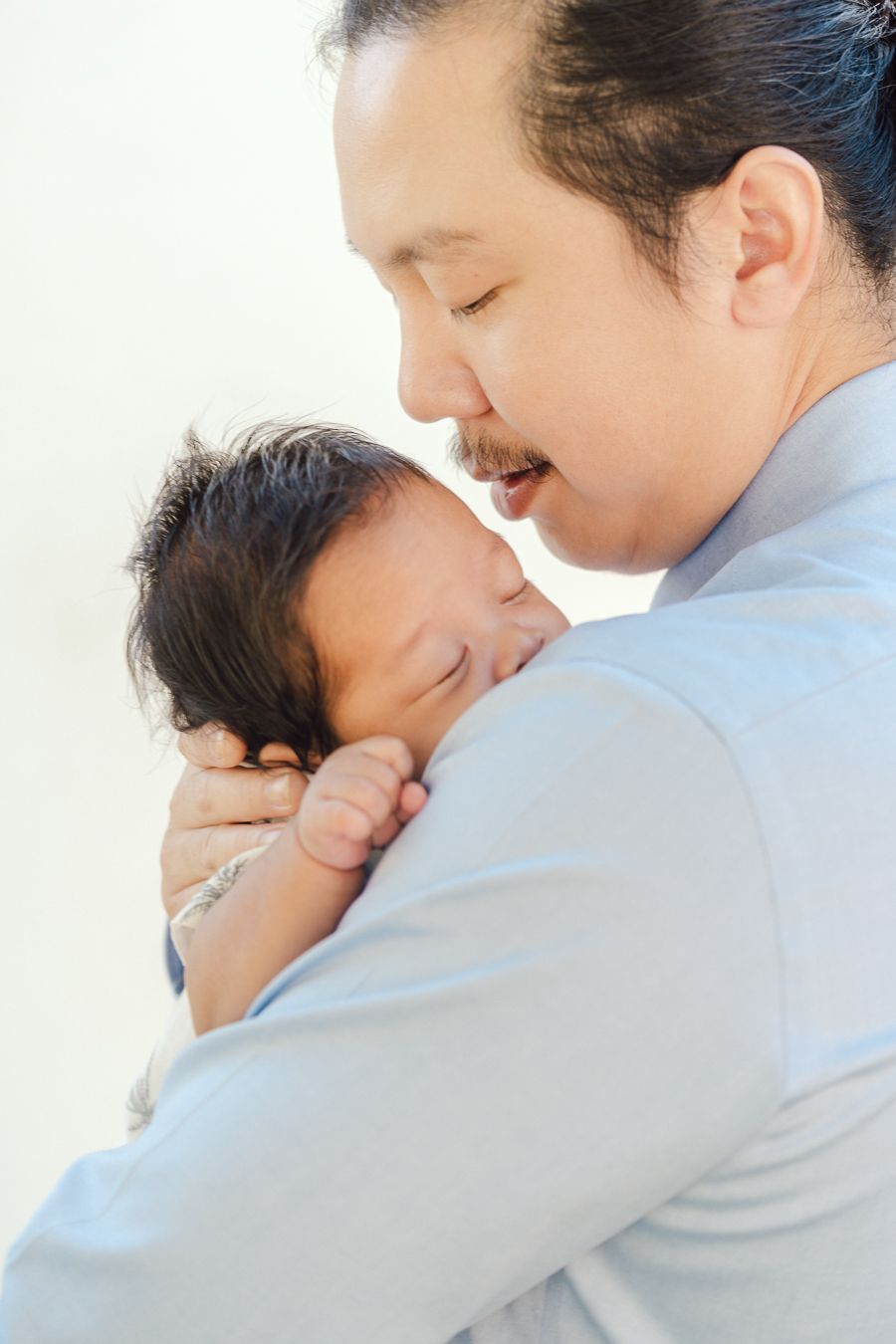 A tender moment between parent and child sharing a gentle embrace against a white background.