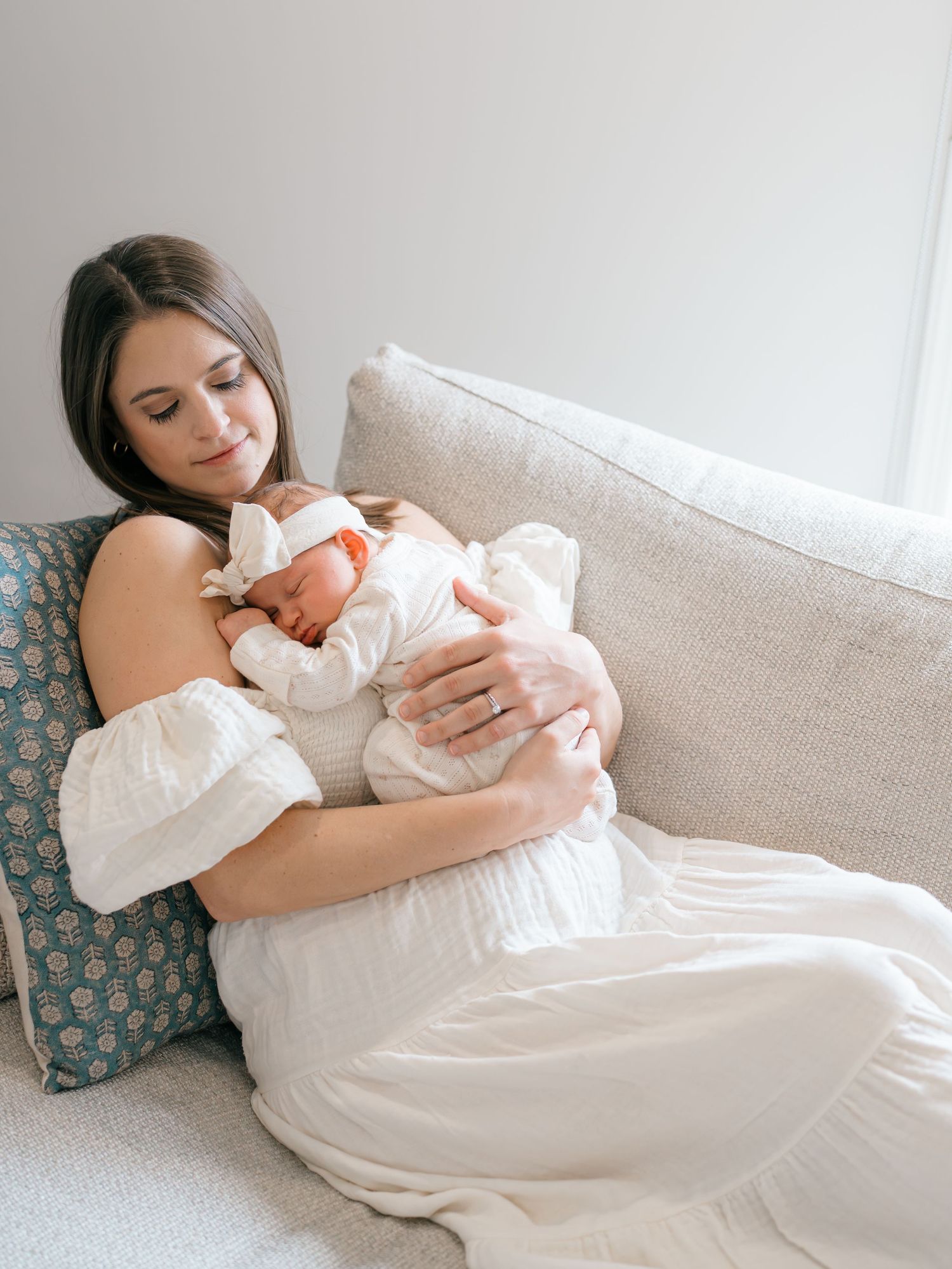 A mother snuggles on the couch on a winter morning with her newborn baby.