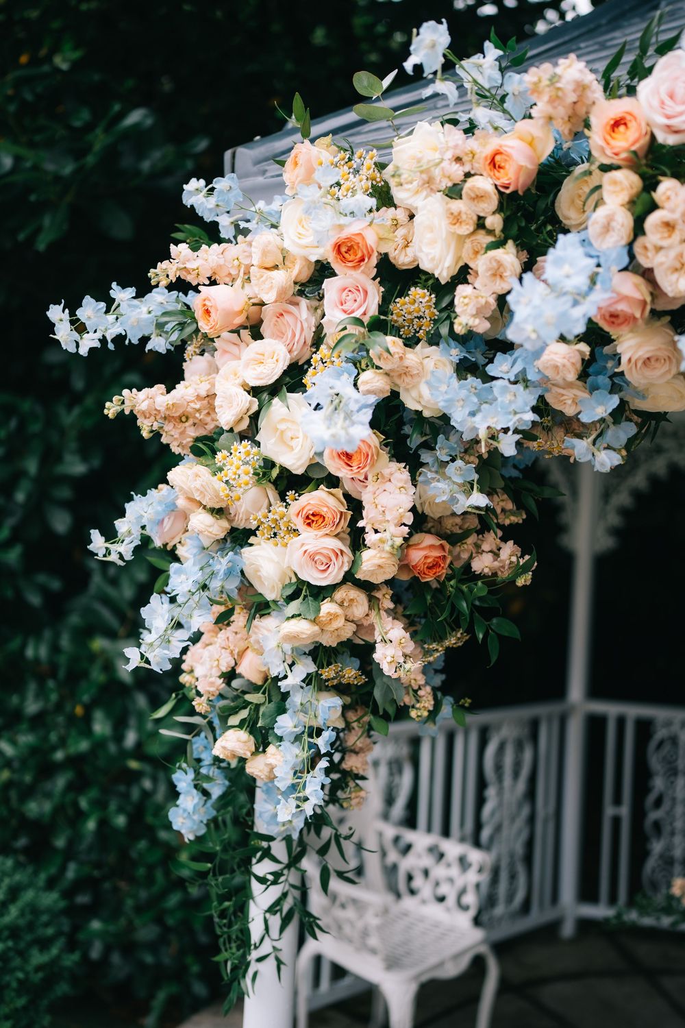 Elegant floral arch with peach roses and white blooms against a garden backdrop at Pendrell Hall wedding venue