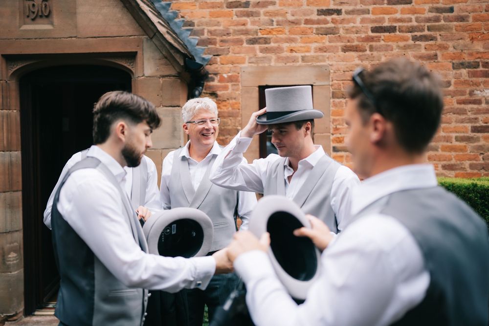 Groomsmen in formal attire gather outside brick building before ceremony at Pendrell Hall wedding venue