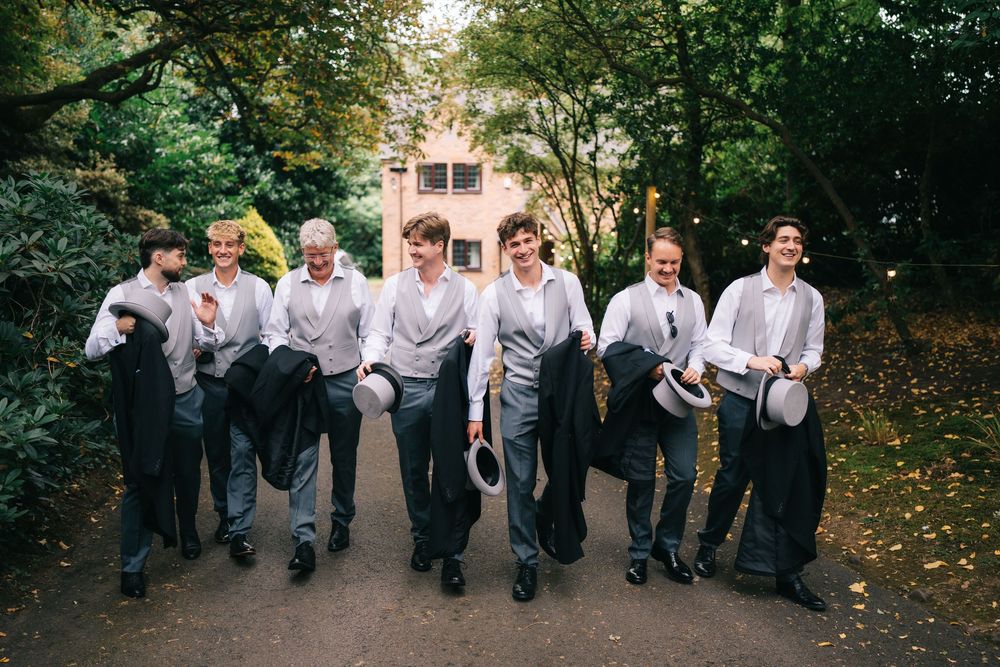 Groomsmen posing casually in a line on tree-lined path during fall wedding at Pendrell Hall wedding venue