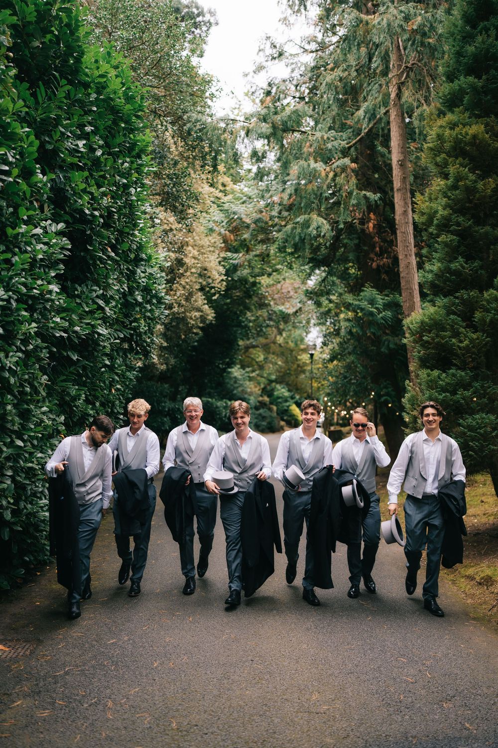 Groomsmen lined up on a tree-lined path posing for a fun group photo at Pendrell Hall wedding venue